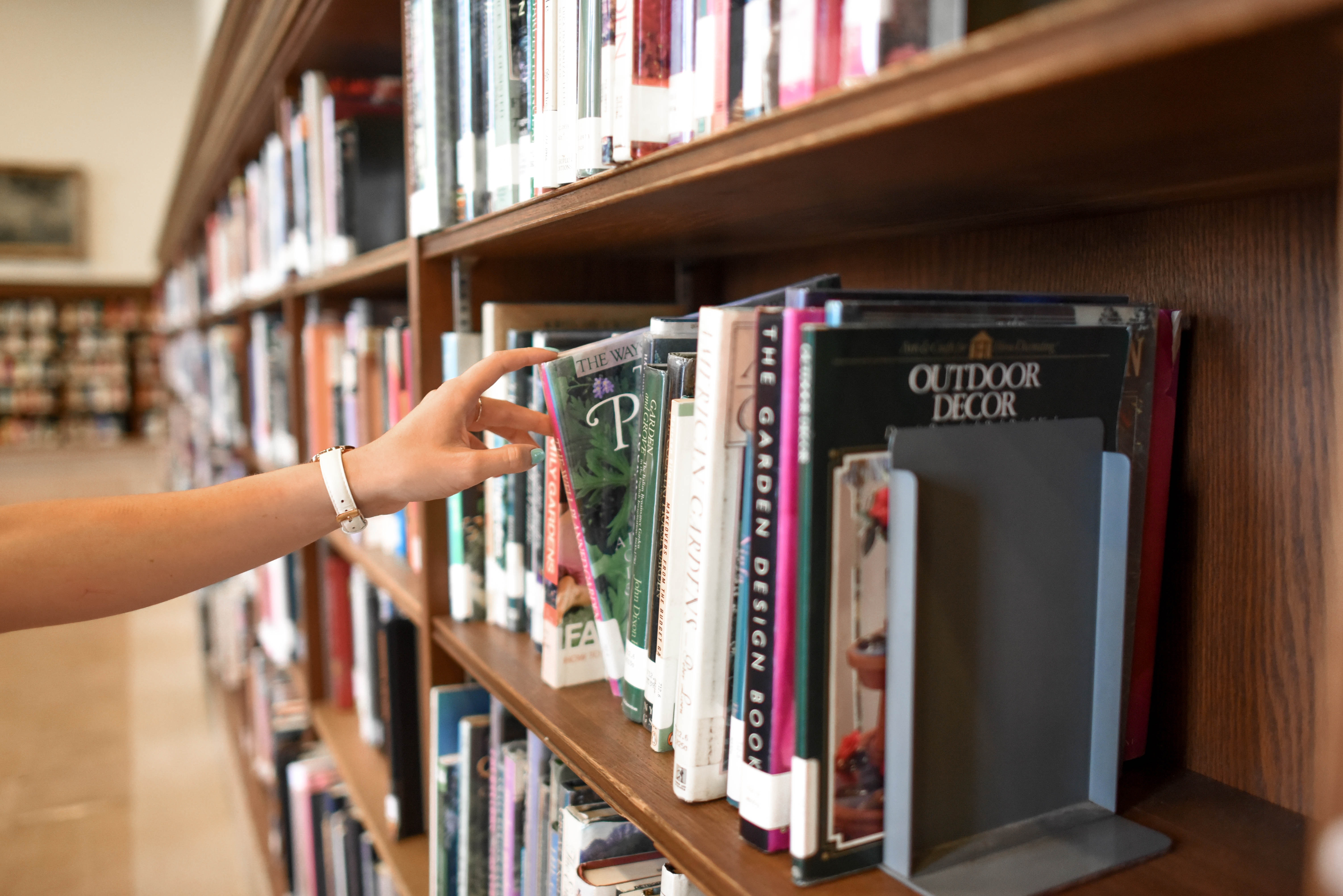 hand reaching for a book on a shelf