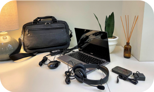 laptop bag chromebook mouse headphones hotspot on a desk with a lamp and a plant