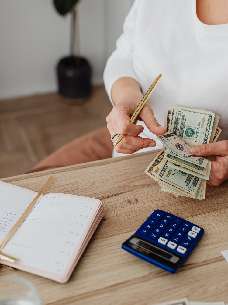 Person budgeting cash with calculator and notebook.