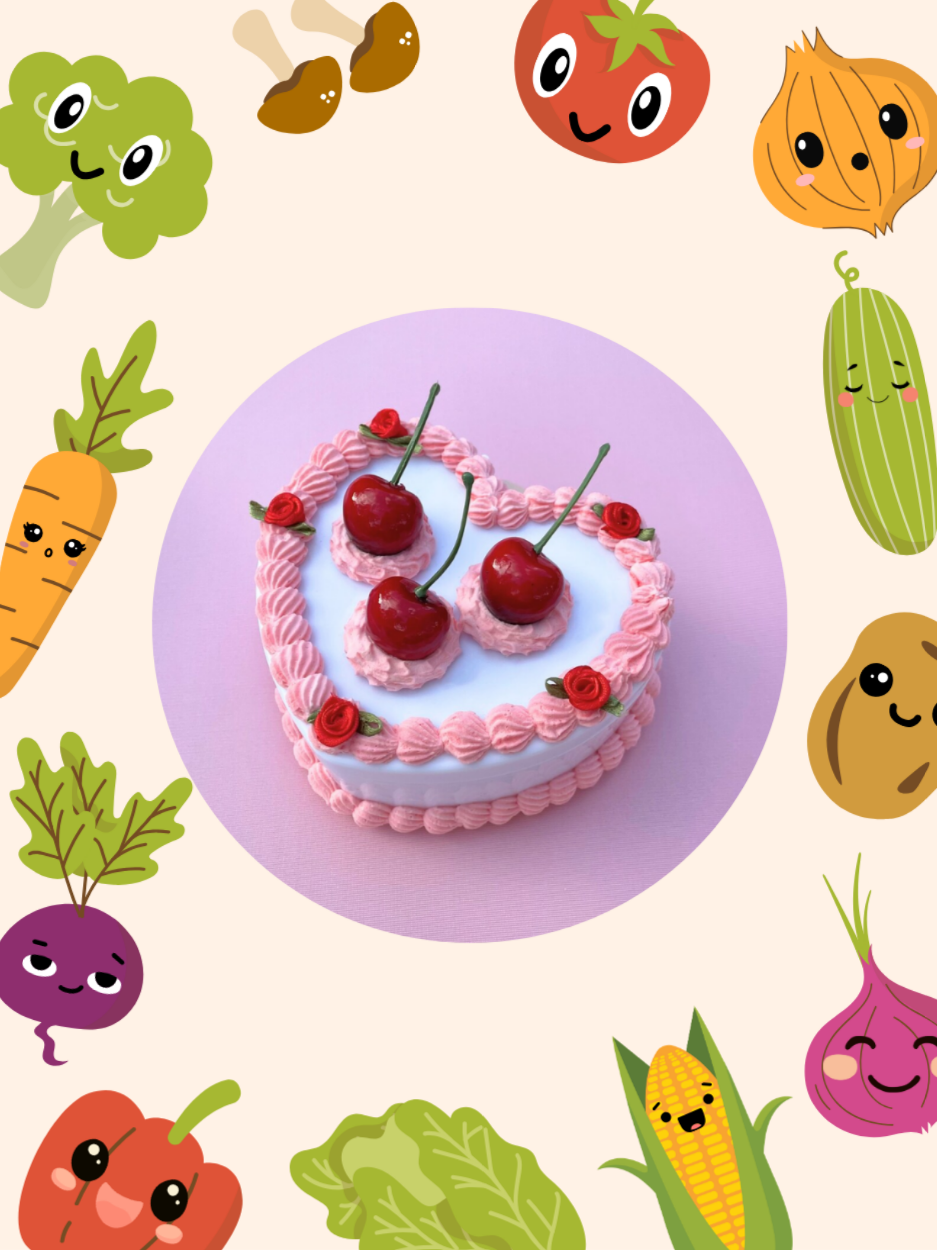 Faux iced cake surrounded by vegetables.