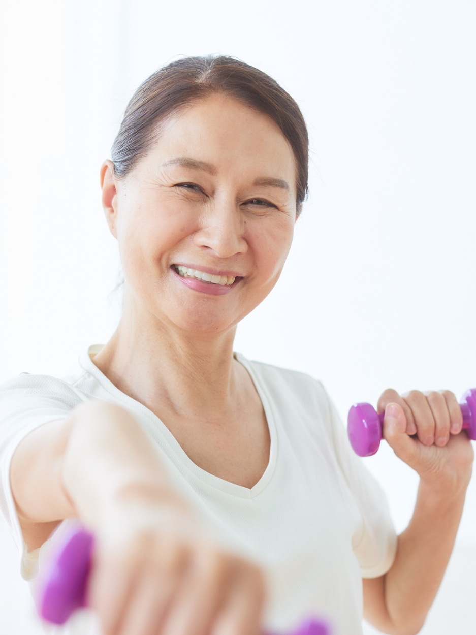 Woman holding hand weights and smiling.