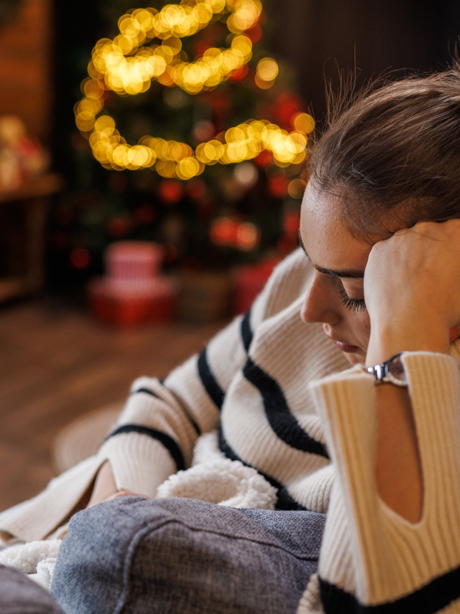 Woman sitting near a Christmas tree.