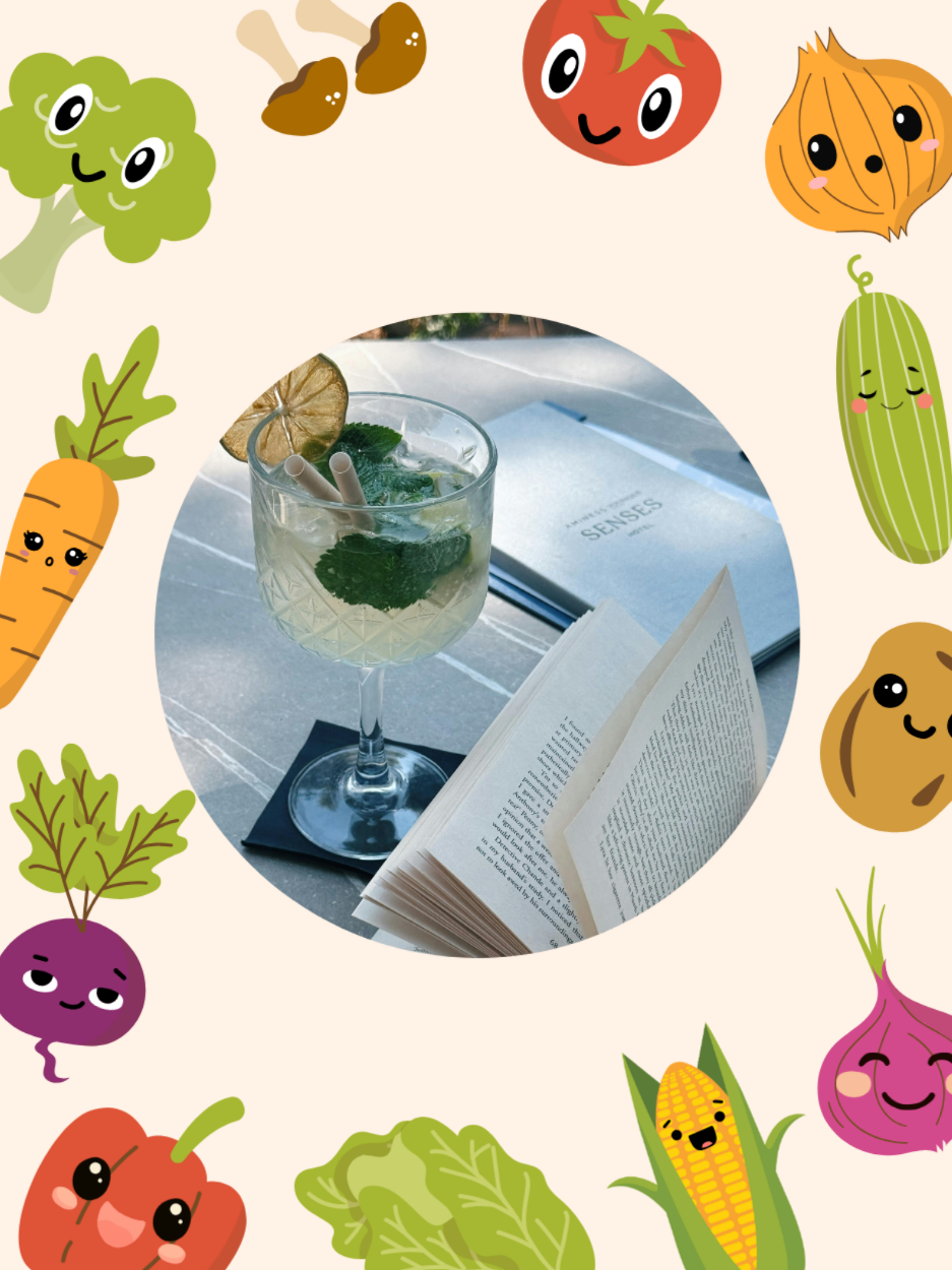 A cocktail and books surrounded by vegetables.