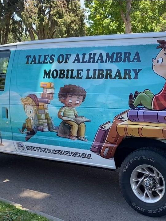 image of library mobile van, a turquoise van with cartoon images of children reading