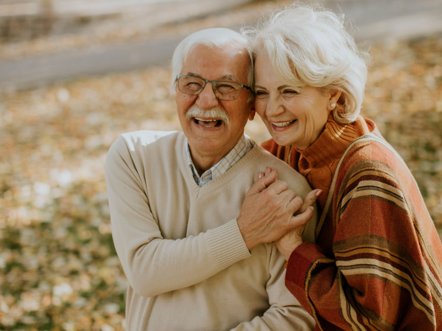 Older man and woman hugging and smiling.