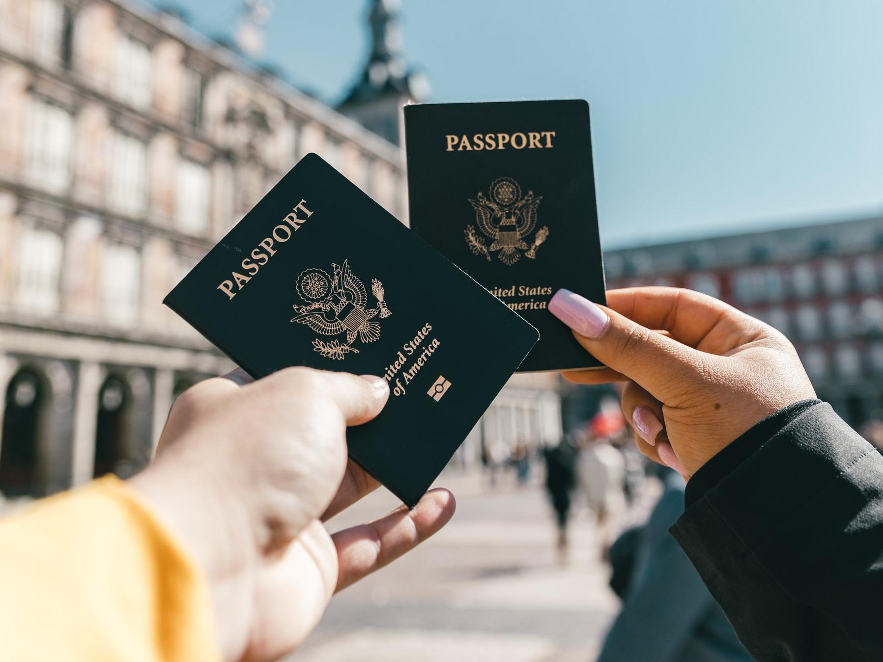 Image of two hands holding US Passports on a sunny day