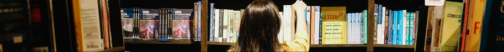 photo of a person reaching for a book on a shelf